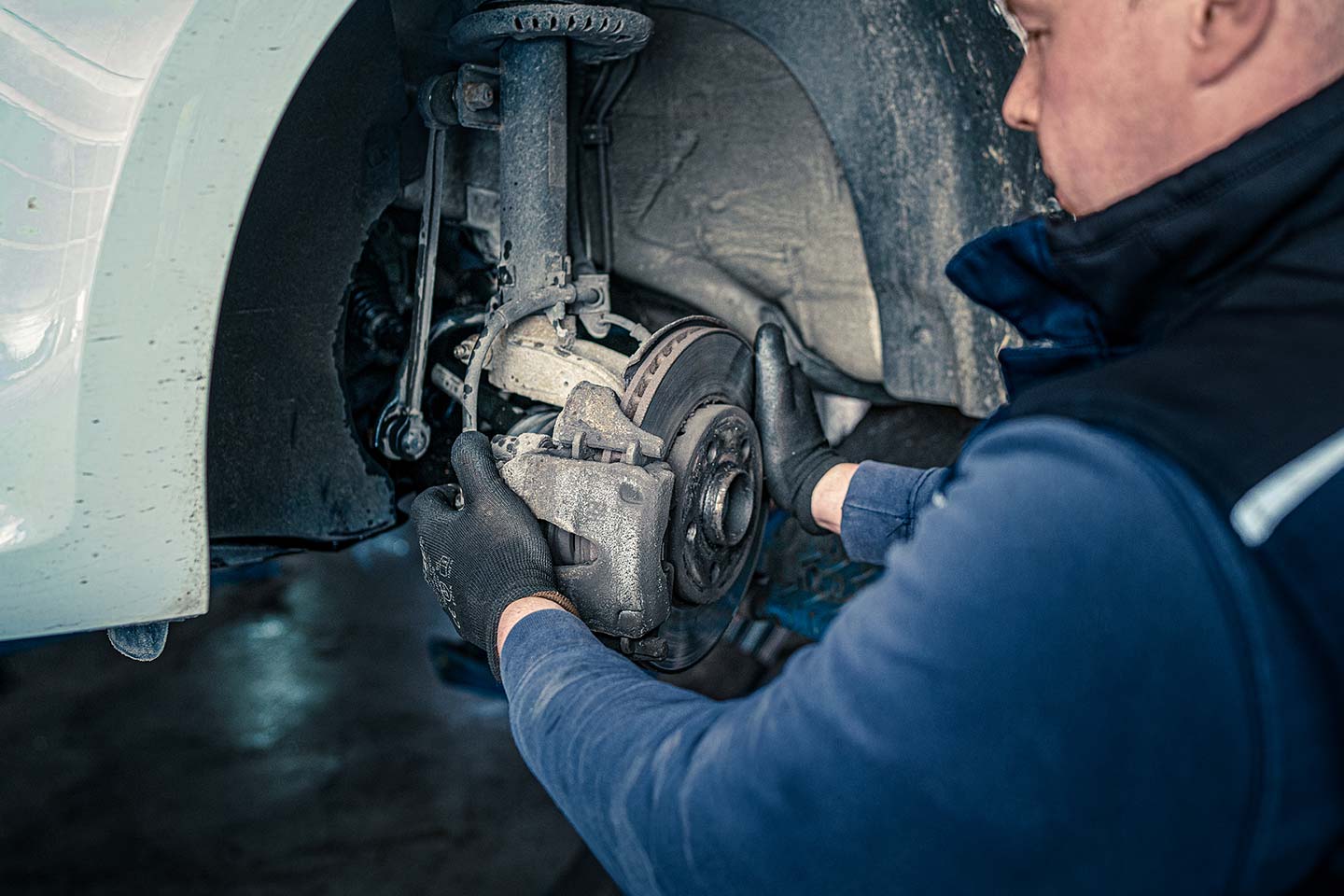 Mechaniker überprüft Bremssattel und Bremsscheibe
