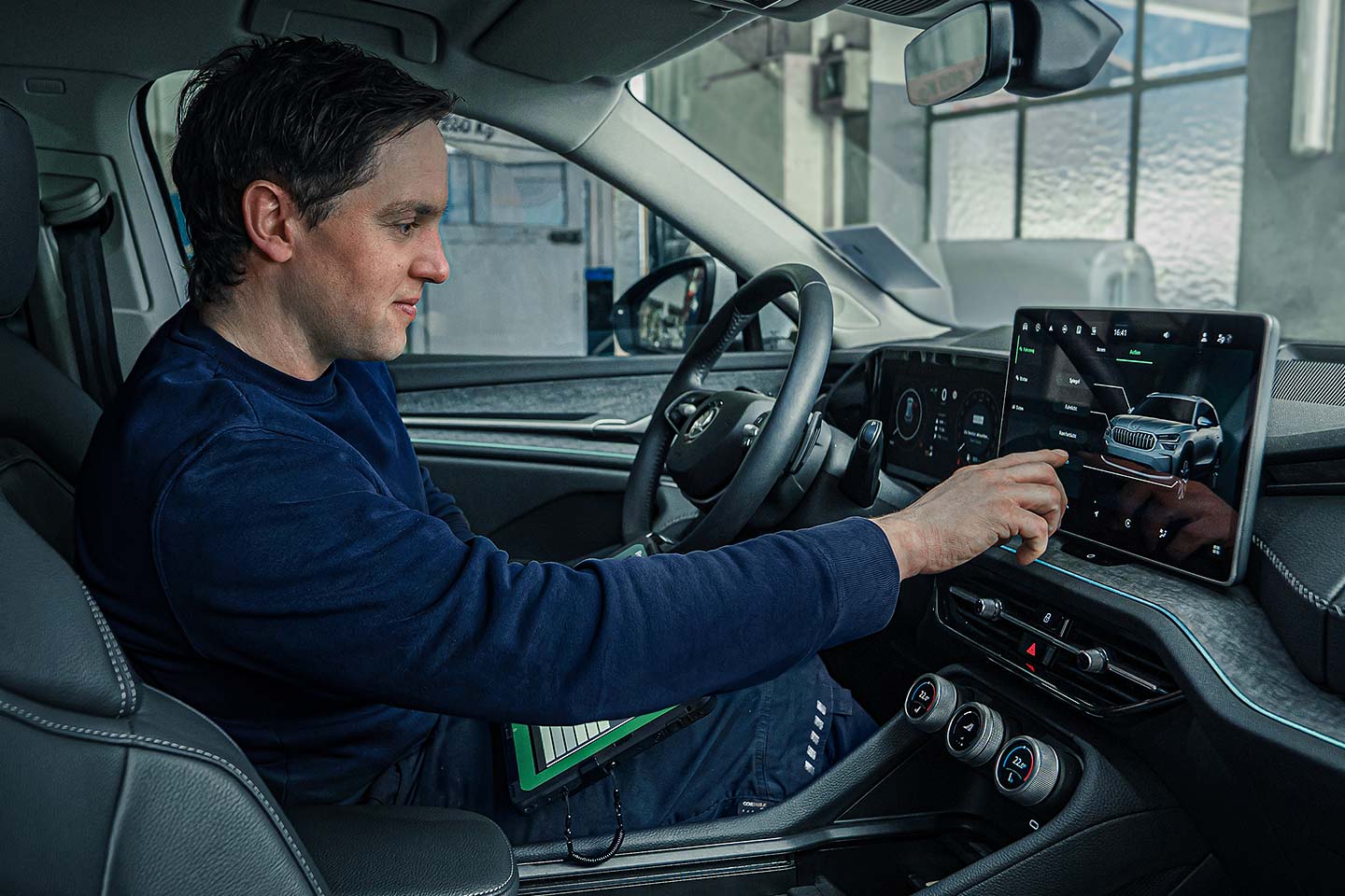 Mechaniker führt Elektronik-Diagnose über Fahrzeugdisplay durch