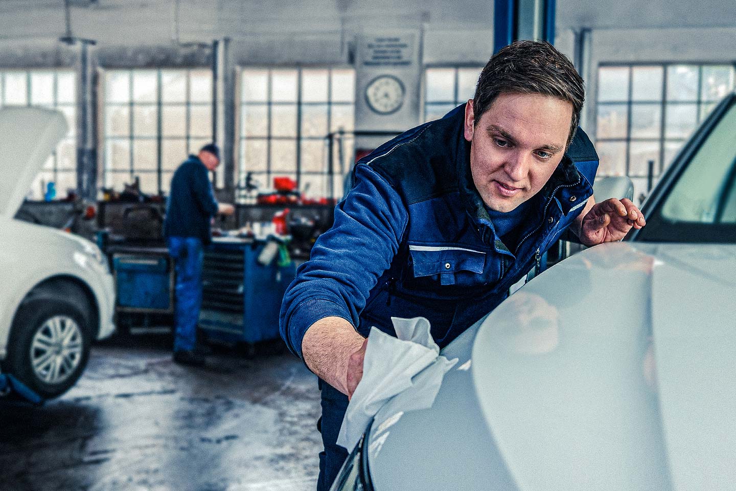 Mechaniker prüft frisch reparierte Fahrzeugfront in der Werkstatt