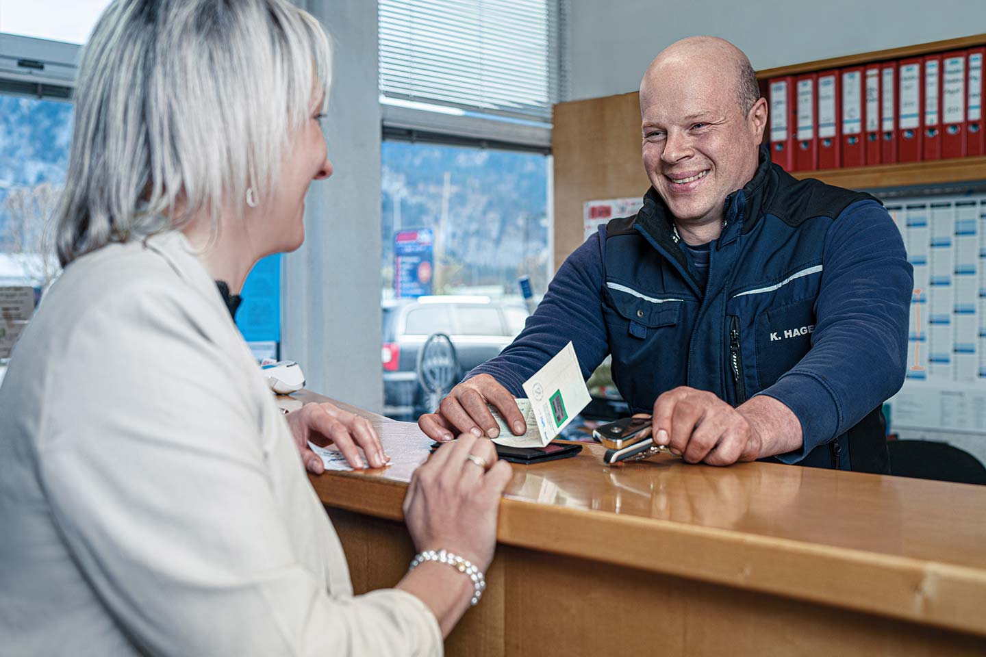 Kundin holt Fahrzeugdokumente im Werkstattbüro ab